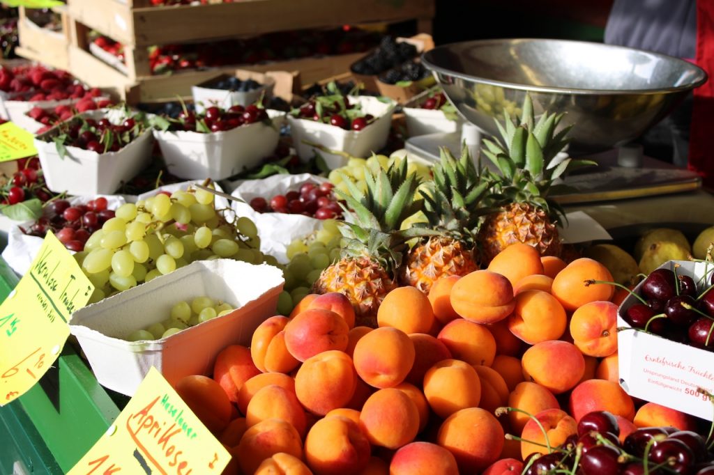 Bild Obstsortiment auf Verkaufsstand mit Aprikosen, Ananas, Trauben und Weitere